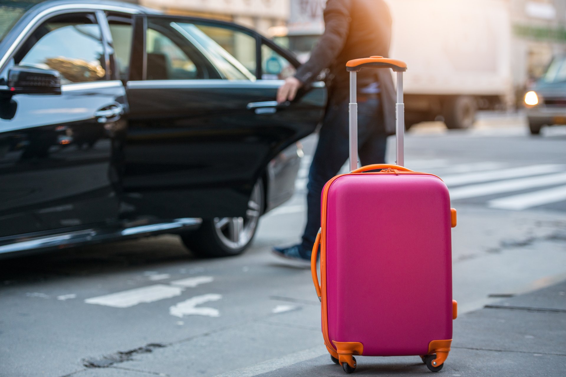 Resväska framför en taxi som någon sätter sig i