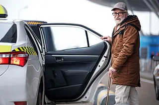 Skäggig man i glasögon kommer att sätt sig i en taxi